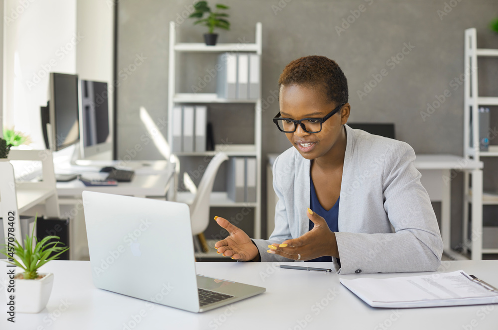 Black woman holding webinar or giving online business consultation to client. Female entrepreneur or corporate company manager having remote online telework meeting via video call on laptop computer