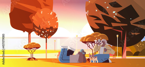 senior couple blowing bubbles and spending time with dog in urban park relaxation retirement concept