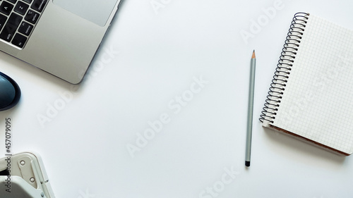 Layout on the topic of working process or education on a white background with notepad, pen, laptop, computer mouse, tablet, hole punch, headphones, pencil