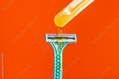 Sugar paste for hair removal against a razor. Sugaring paste drips on the razor. The concept of epilation, spa, body care.