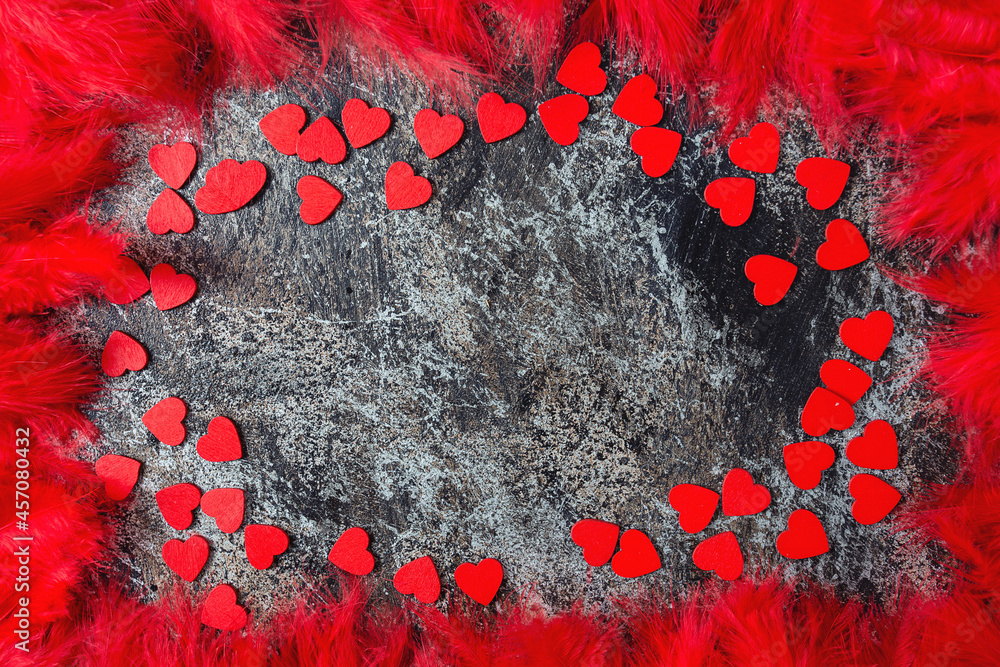 Obraz na plátně red feathers and wooden hearts on stone surface