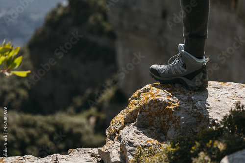 Hiking shoe stepping on a small rock with blurred landscape background on sunny day. Copy space.