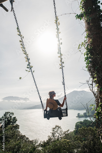 A girl rides on a swing with a gorgeous view of the valley, Bali.