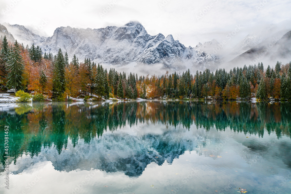 Between autumn and winter. Warm and cold reflections of snow on Lake Fusine.