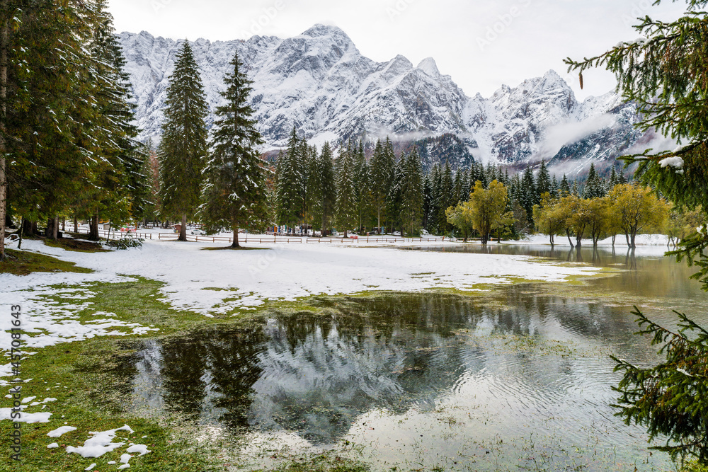 Between autumn and winter. Warm and cold reflections of snow on Lake Fusine. Between autumn and winter. Warm and cold reflections of snow on Lake Fusine.