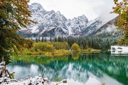Between autumn and winter. Warm and cold reflections of snow on Lake Fusine.