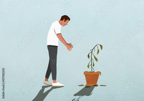 Surprised man looking down at dead houseplant
