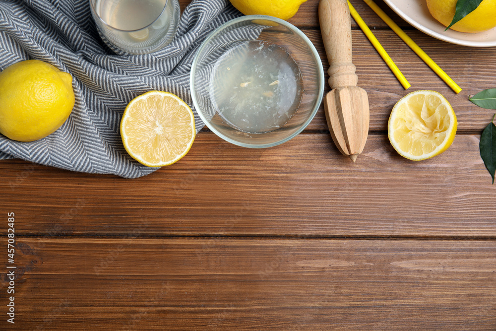 Citrus reamer, juice and fresh lemons on wooden table, flat lay. Space for text Citrus reamer, juice and fresh lemons on wooden table, flat lay. Space for text