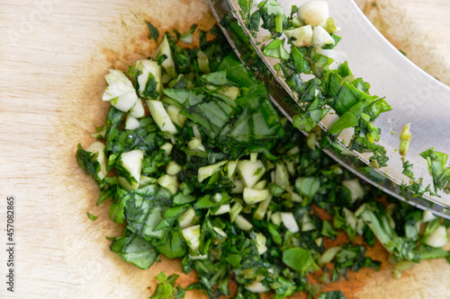 Basil and garlic are finely chopped using a double mezzaluna knife and board. photo