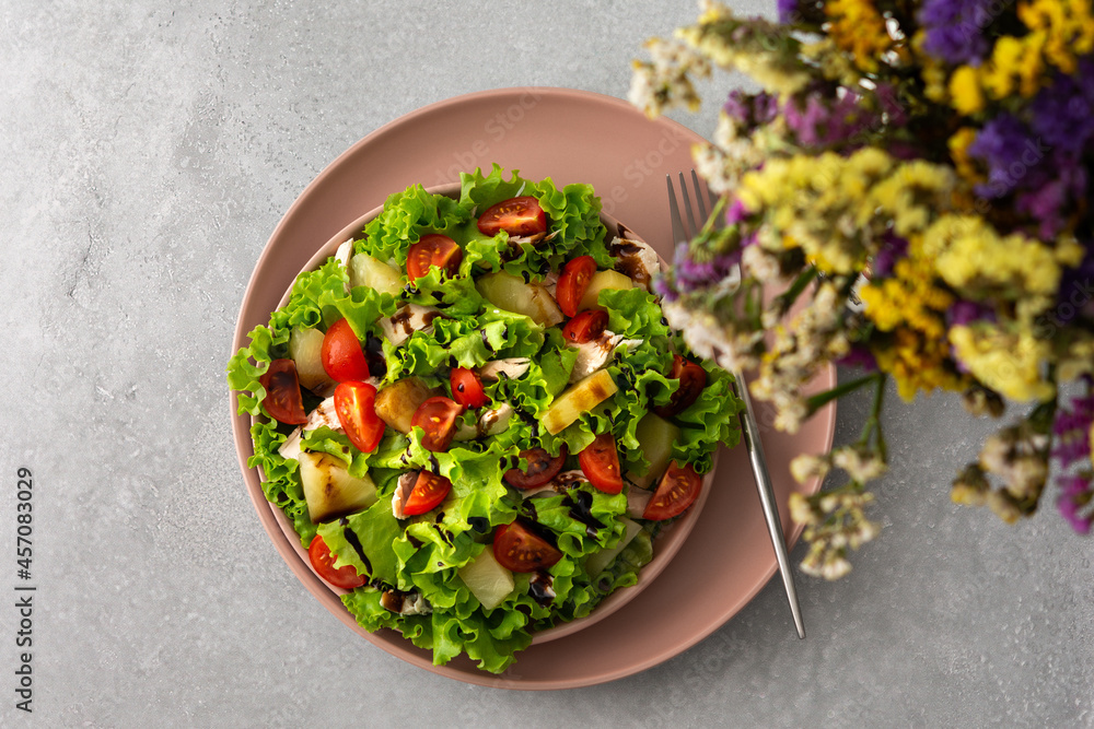 Light summer fresh salad with tomatoes and lettuce, chicken breast and pineapple with balsamic sauce, top view