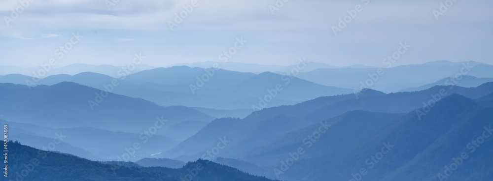 Beautiful blue mountain landscape with fog and forest.