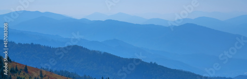 High peaks of blue mountain range landscape with fog. Horizontal image.