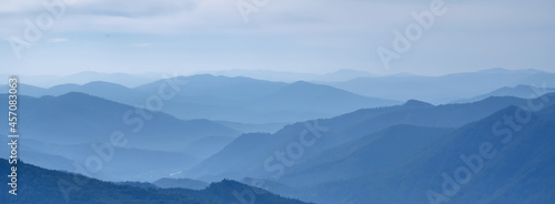 Beautiful blue mountain landscape with fog and forest. © zwiebackesser
