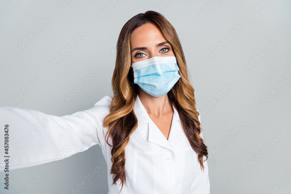 Photo of mature happy woman hold hand camera selfie face doctor wear mask isolated on grey color background Photo of mature happy woman hold hand camera selfie face doctor wear mask isolated on grey color background