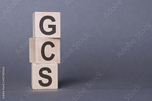 GCS (Glasgow Coma Scale) - text, written on wooden blocks, on gray background. photo