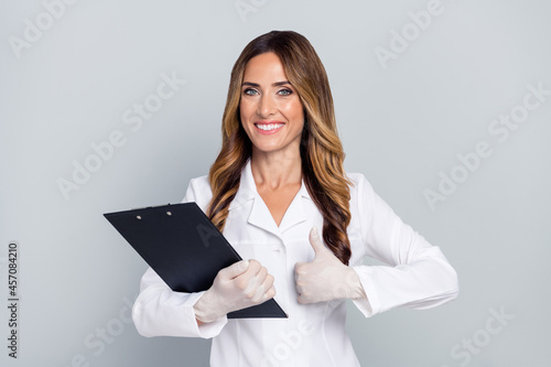 Portrait of attractive cheery woman doc holding document showing thumbup isolated over grey pastel color background