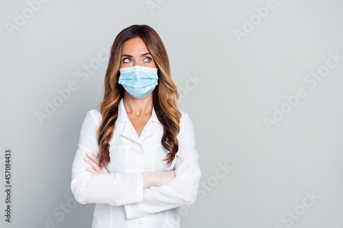Photo of dreamy positive age lady doctor wear white formal coat arms crossed looking empty space isolated grey color background
