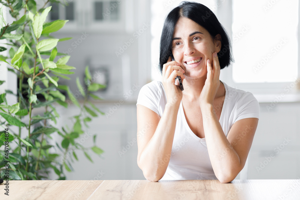 Happy woman smiling and holding smartphone in hands, young lady chatting in social networks online, watching funny videos in the internet, using mobile applications at home Happy woman smiling and holding smartphone in hands, young lady chatting in social networks online, watching funny videos in the internet, using mobile applications at home