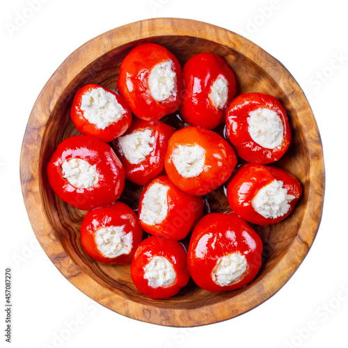 Small red cherry peppers stuffed with soft cheese in wooden bowl isolated on white background. Top view. photo