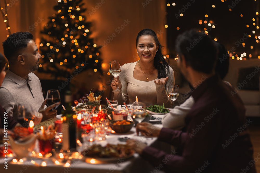 holidays, party and celebration concept - multiethnic group of happy friends having christmas dinner at home and drinking wine holidays, party and celebration concept - multiethnic group of happy friends having christmas dinner at home and drinking wine