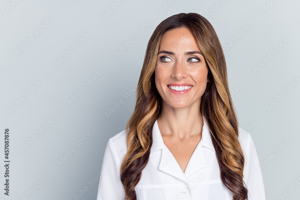 Portrait of attractive skilled cheerful wavy-haired woman doc looking aside copy space isolated over grey color background Portrait of attractive skilled cheerful wavy-haired woman doc looking aside copy space isolated over grey color background