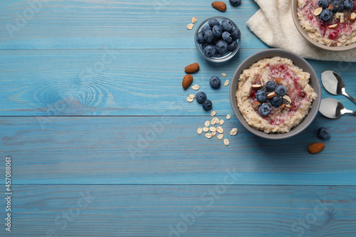 Tasty oatmeal porridge with toppings on light blue wooden table, flat lay. Space for text