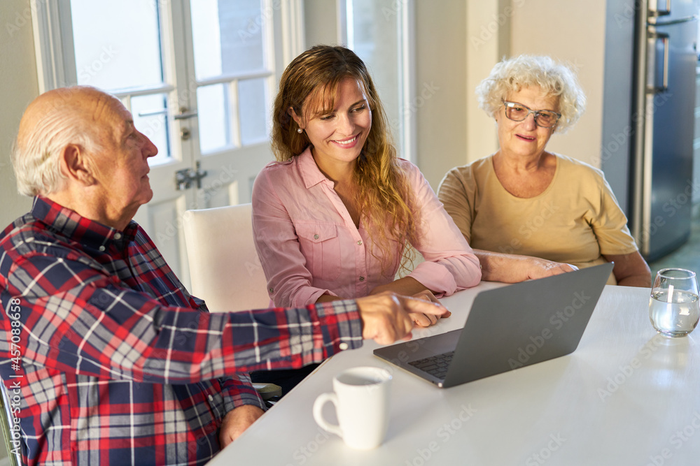 Obraz premium Curious senior couple with daughter on laptop computer