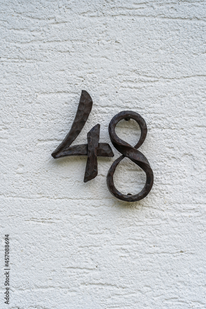 Metal house number 48 on a white stucco wall background Metal house number 48 on a white stucco wall background
