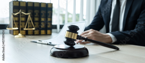 Counselor lawyer or notary working on a documents and report of the important case and wooden gavel, brass scale on table in courtroom © Ngampol