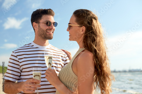 leisure, relationships and people concept - happy couple in sunglasses drinking champagne on summer beach