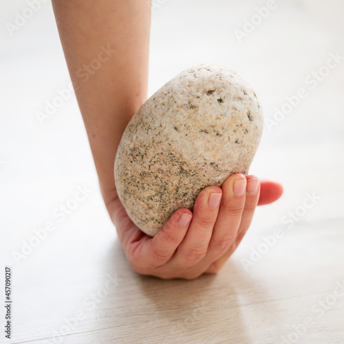 Hands hold a round stone close up