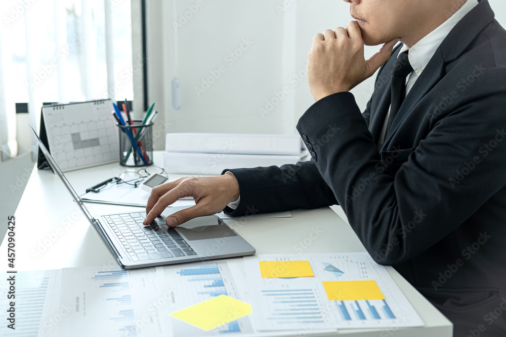 Businessman boss in suit is thinking and analysis of investments in new business from chart during to typing Businessman boss in suit is thinking and analysis of investments in new business from chart during to typing