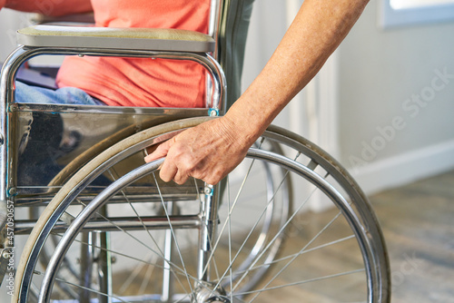 Hand of a patient with stroke on the wheel of a wheelchair