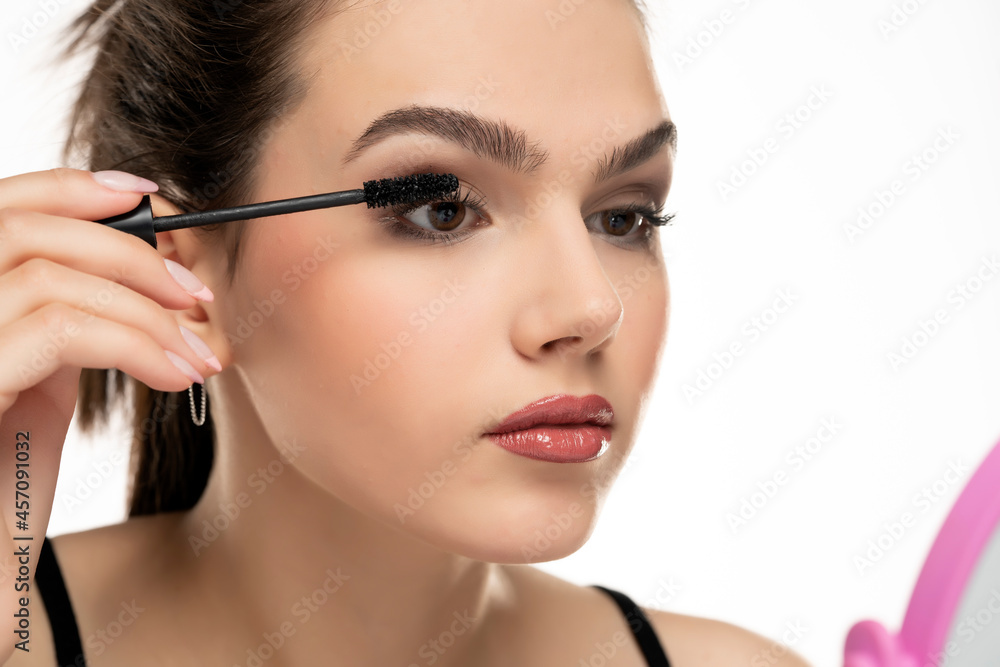 portrait of a teen girl applying mascara on her eyelashes
