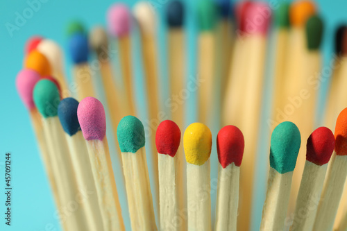 Matches with colorful heads on light blue background, closeup