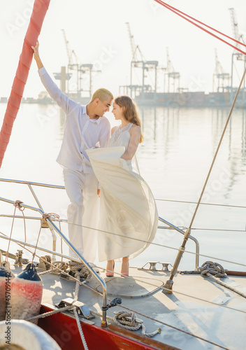 couple stands on board the yacht against the backdrop of the seaport