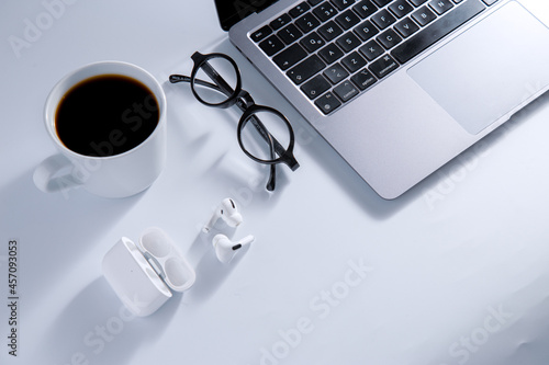 Business geek concept with laptop and earphones, coffee and glasses. Flat lay view.