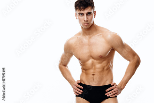 handsome man with a pumped-up torso holding his hands on his belt on isolated background cropped view