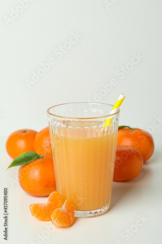 Glass of mandarin juice and ingredients on white background