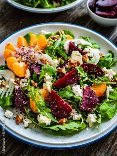  Beetroots salad with feta cheese  walnuts and tangerines on wooden background 