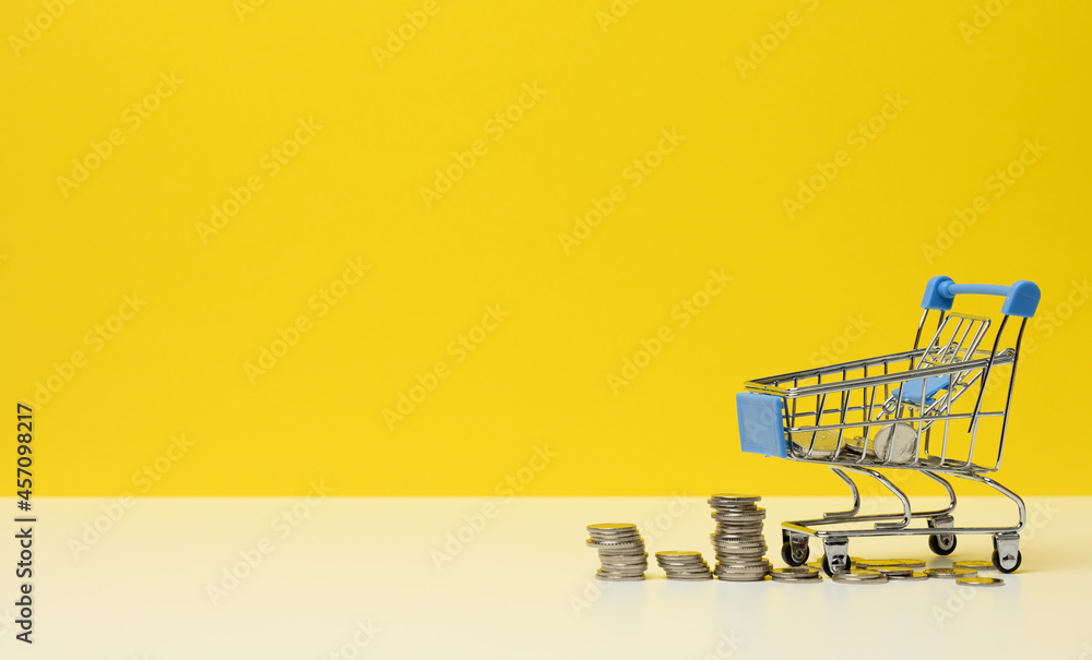 metal trolley and small change on a white table. Savings concept, discounts, low purchasing power metal trolley and small change on a white table. Savings concept, discounts, low purchasing power