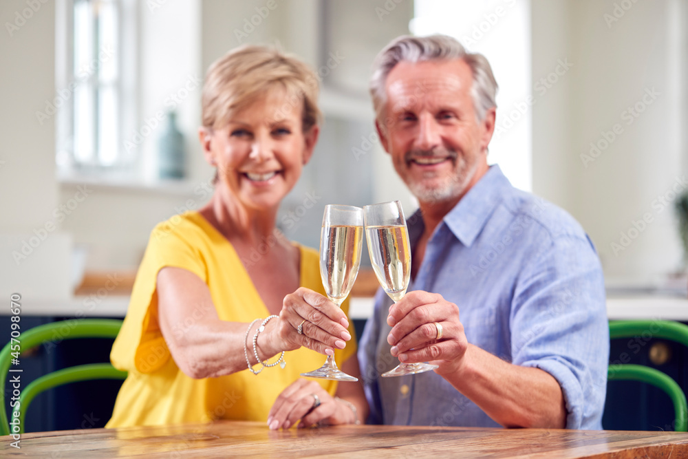 Portrait Of Retired Couple Celebrating With Glass Of Champagne At Home On Date Night Together