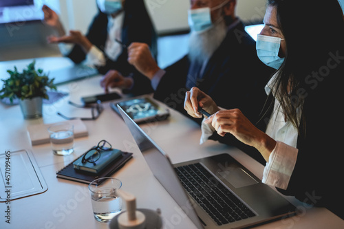 Business teamwork doing blockchain analysis inside fintech company office wearing safety mask during coronavirus outbreak - Soft focus on woman face