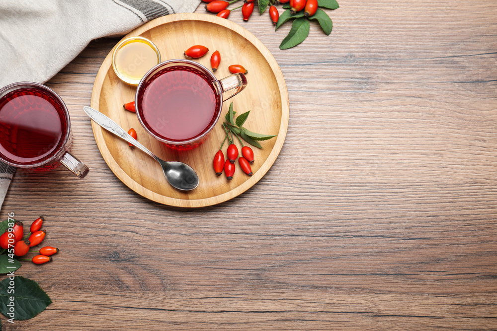Fresh rose hip tea, honey and berries on wooden table, flat lay. Space for text Fresh rose hip tea, honey and berries on wooden table, flat lay. Space for text