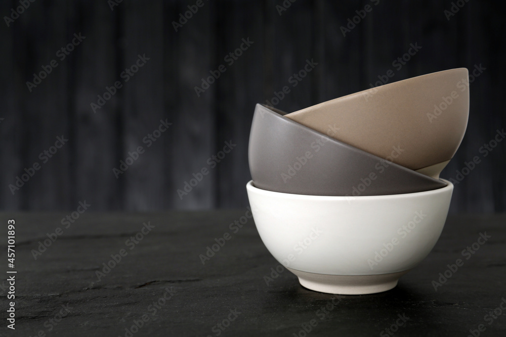 Stylish empty ceramic bowls on black table, space for text. Cooking utensils - obrazy, fototapety, plakaty 
