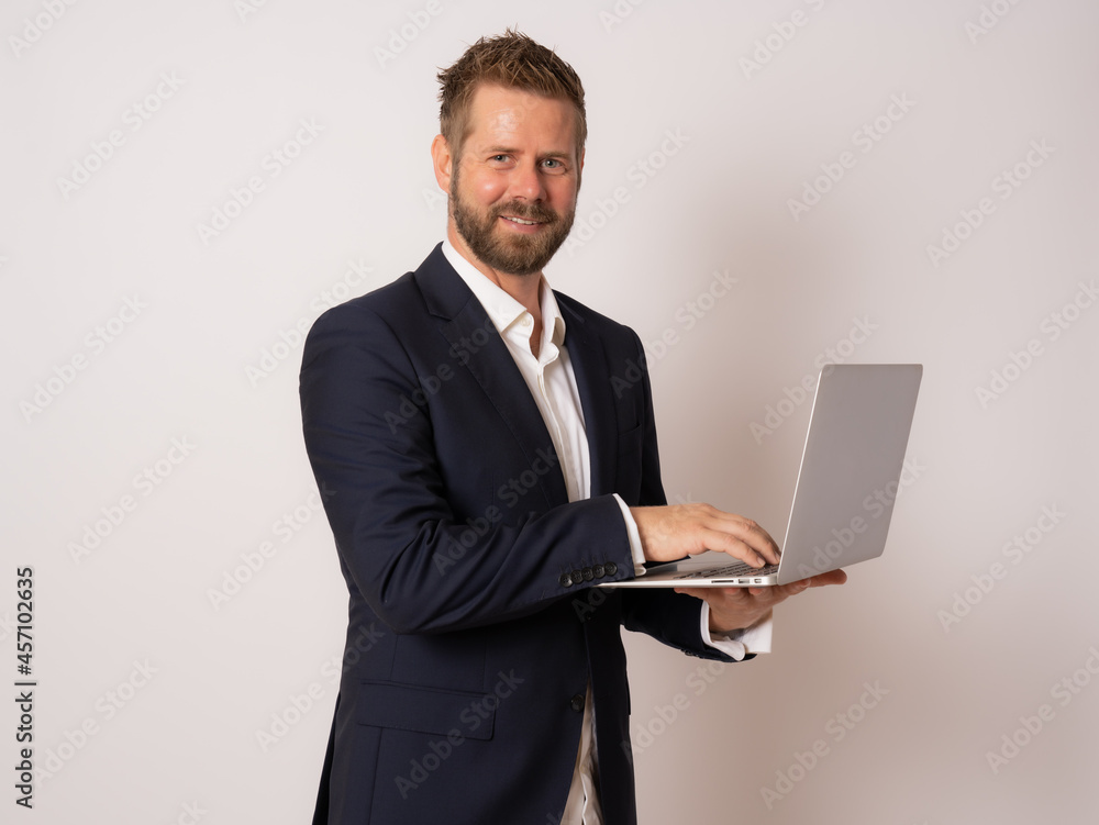 Young business man standing with laptop. Handsome guy holding open notebook in his hand and work on it. Information, technology concept. Young business man standing with laptop. Handsome guy holding open notebook in his hand and work on it. Information, technology concept.