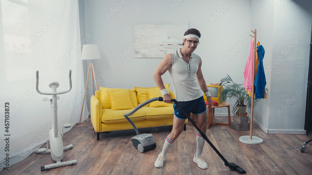 happy sportsman dancing while vacuum cleaning living room, retro sport concept happy sportsman dancing while vacuum cleaning living room, retro sport concept