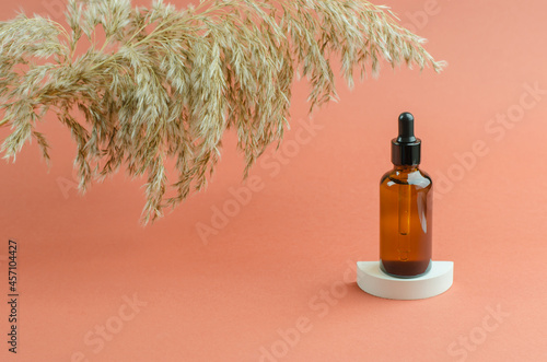 A bottle of scented oil on a white podium. Essential oil or serum in a brown bottle with a dropper. Cosmetics, body care.