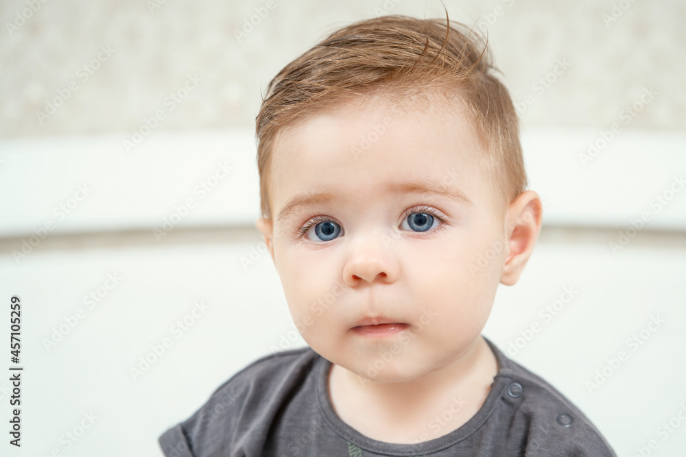 Close-up portrait of a little Caucasian baby boy. Healthy serious funny toddler lovely kid concept. Red haired kid in t-shirt looking at camera.