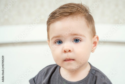 Close-up portrait of a little Caucasian baby boy. Healthy serious funny toddler lovely kid concept. Red haired kid in t-shirt looking at camera.